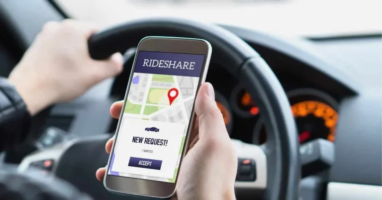 Image showcasing a drivers hand holding a mobile phone and a ride hailing app is opened currently.